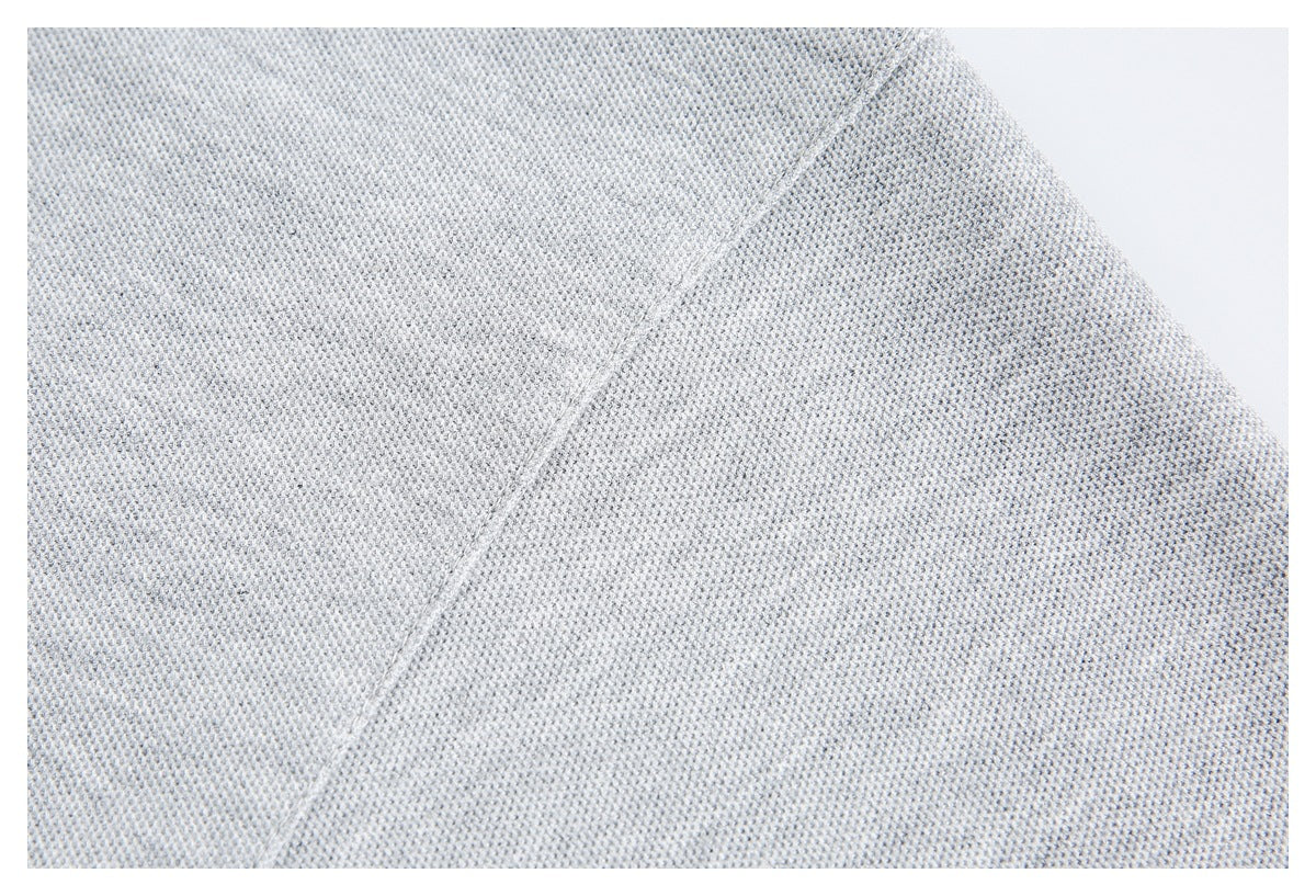 Close-up of pale gray knit fabric showing its small textured stitches and a diagonal seam.