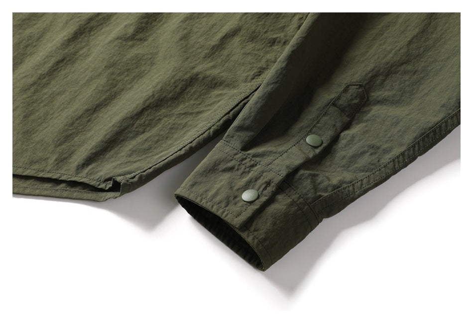Close-up of the dark olive shirt's curved hem and cuff with two snap buttons.