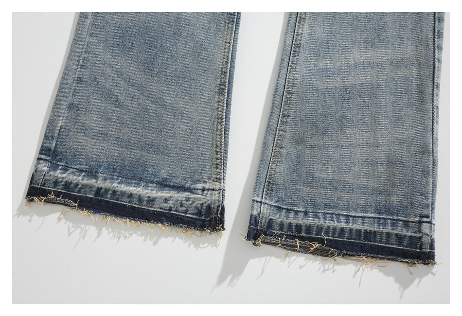 Close-up of light blue washed jean legs with dark, frayed raw hems.