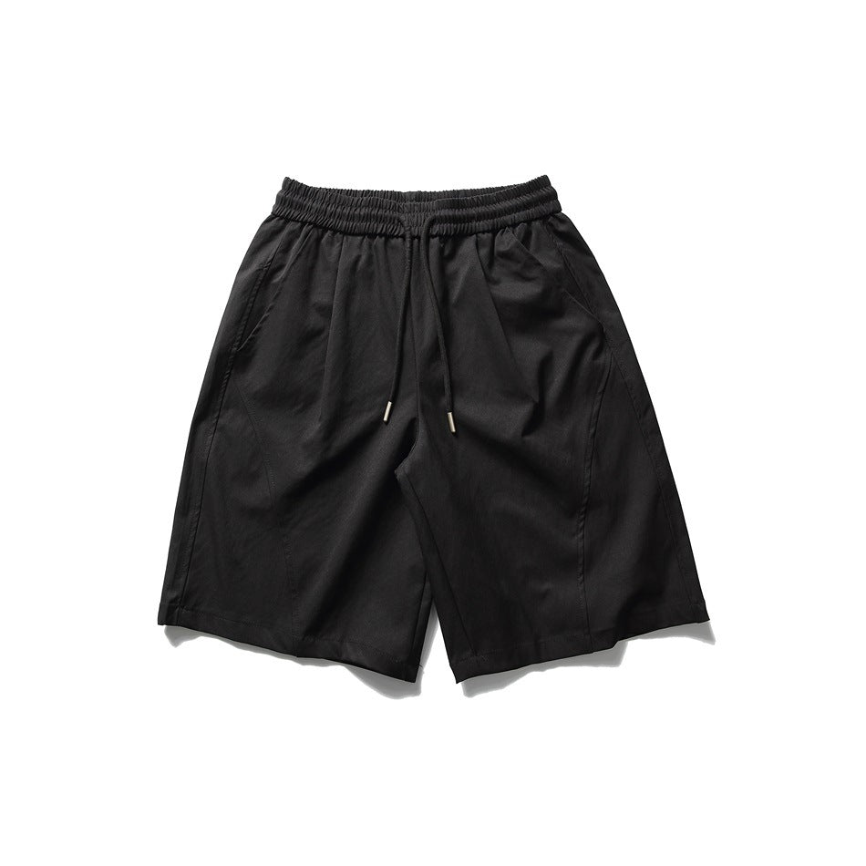Black knee-length shorts with elastic drawstring waist, curved front seams and side pockets, flat lay front view