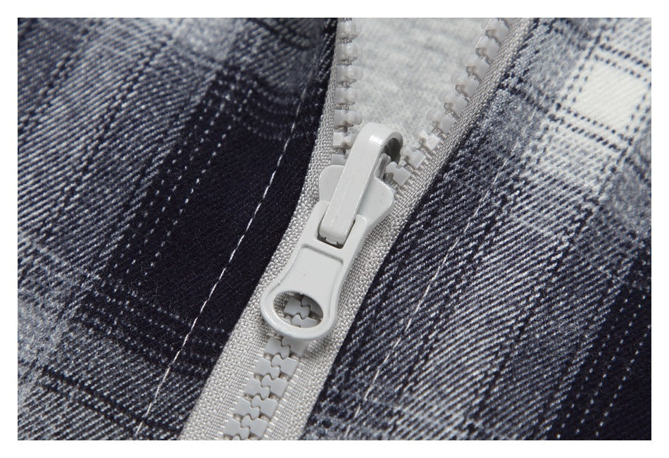 Close-up of a light gray zipper on a black, gray, and white plaid garment.