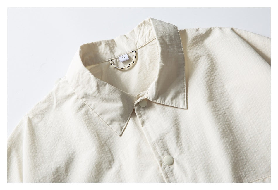 Close-up of an ivory shirt collar, top buttons, and subtle textured fabric.