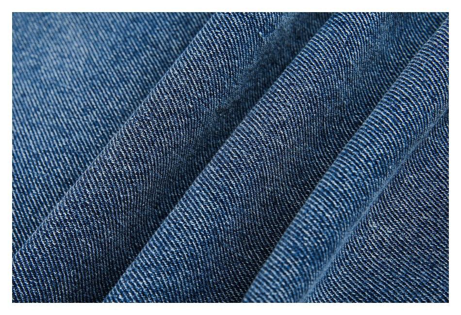 Close-up of blue denim fabric showing its diagonal twill weave and folded texture.