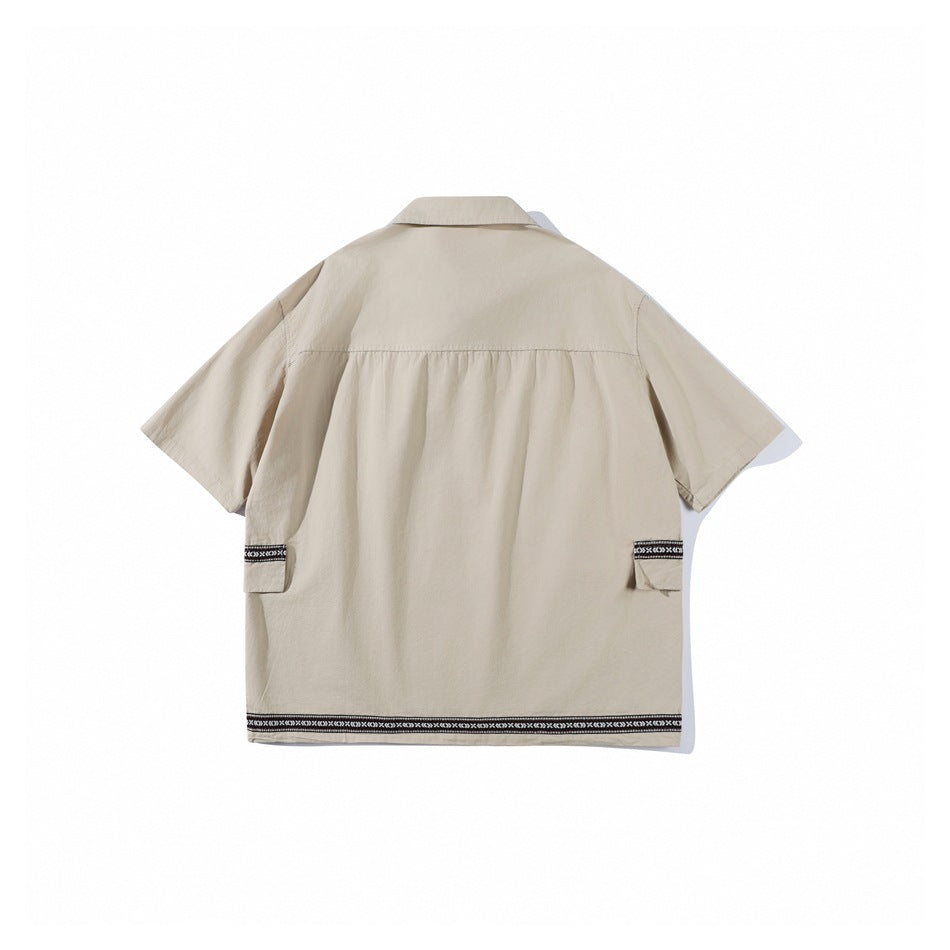 Back view of the apricot short-sleeve shirt with back yoke, side flap pockets and woven trim along the hem, flat lay