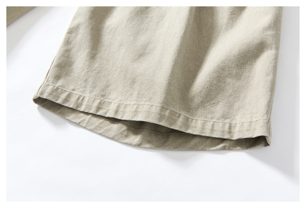 Close-up of the straight stitched hem on a light khaki garment leg.