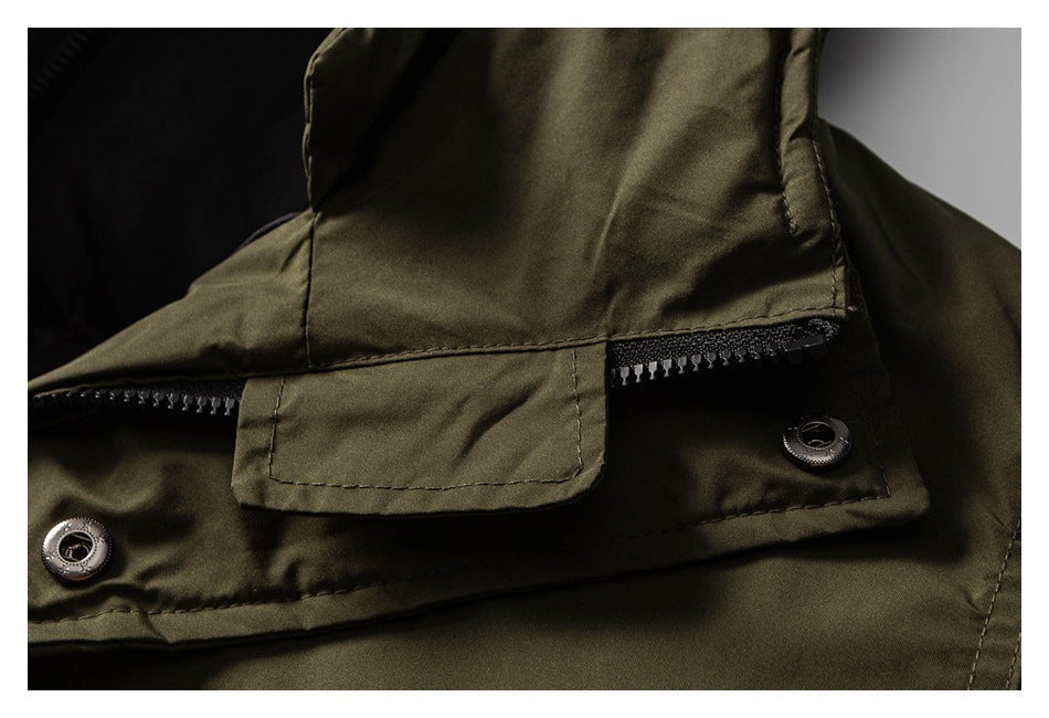 Close-up of an olive jacket front with a zipper beneath a flap and metal snaps.