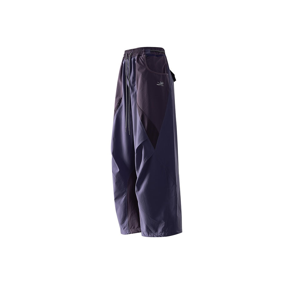 Angled front view of dark purple wide-leg pants with an elastic drawstring waist, curved panels, and a small garment logo.