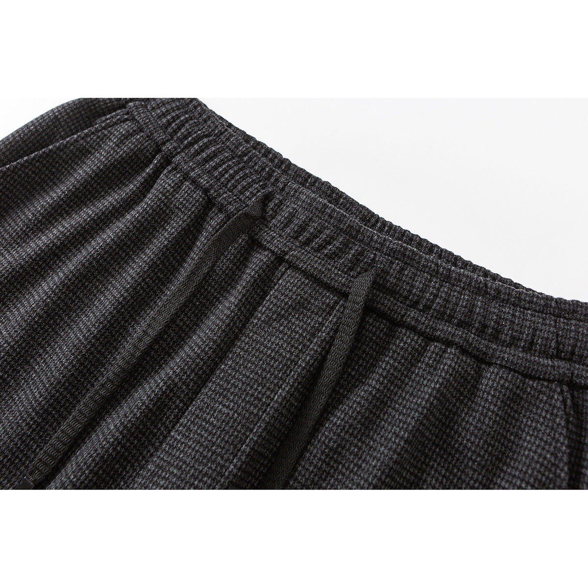 Close-up of charcoal gray patterned trousers showing the elastic waistband, drawstring, and pleats.