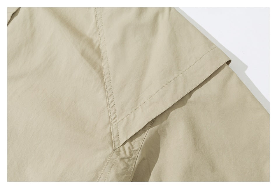 Close-up of a light beige garment with stitched seams and an overlapping fabric panel.