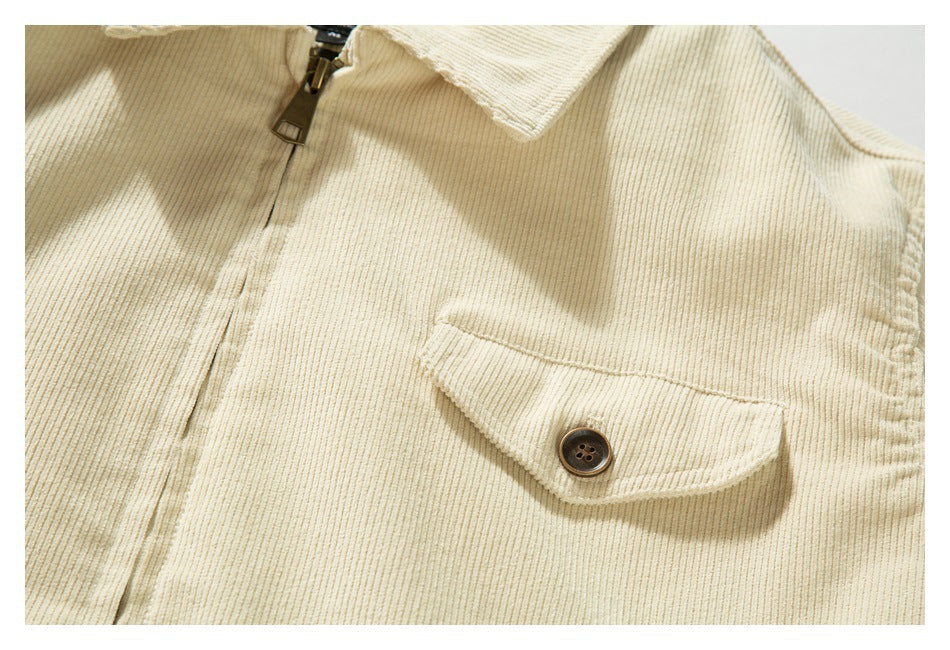 Close-up of a cream ribbed jacket with a button-flap chest pocket and front zipper.