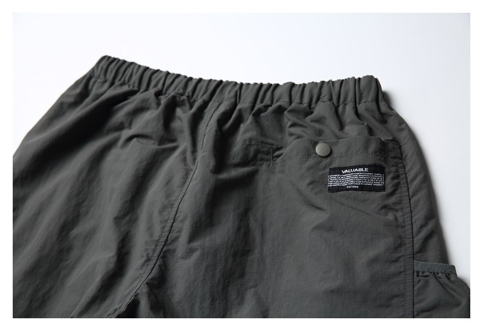 Upper back of charcoal shorts with an elastic waistband, snap-button pocket, and sewn label.