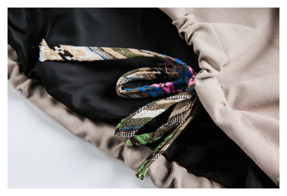 Close-up of a beige garment with a black panel and multicolored woven drawstring.