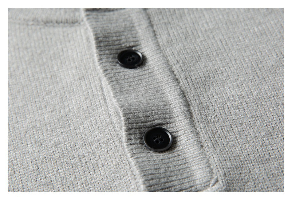 Close-up of two black buttons on the placket of a light gray knit sweater.