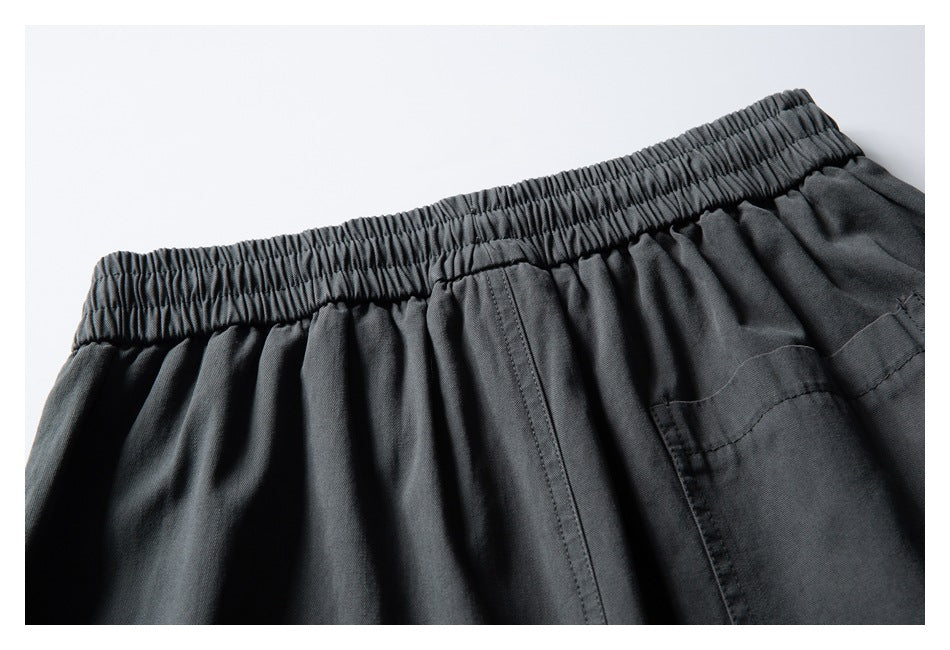 Close-up of dark charcoal pants showing the gathered back waistband and a stitched patch pocket.