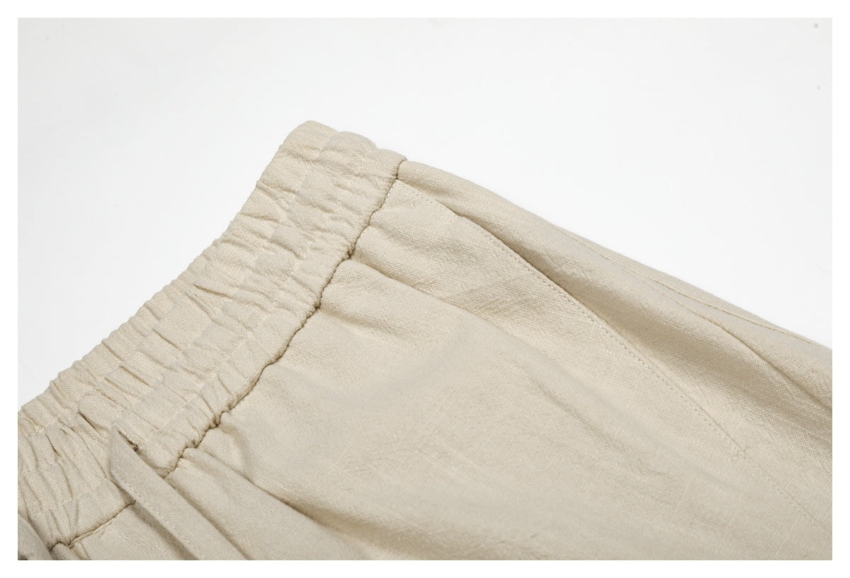 Close-up of beige trousers showing the gathered elastic waistband and angled front seam.