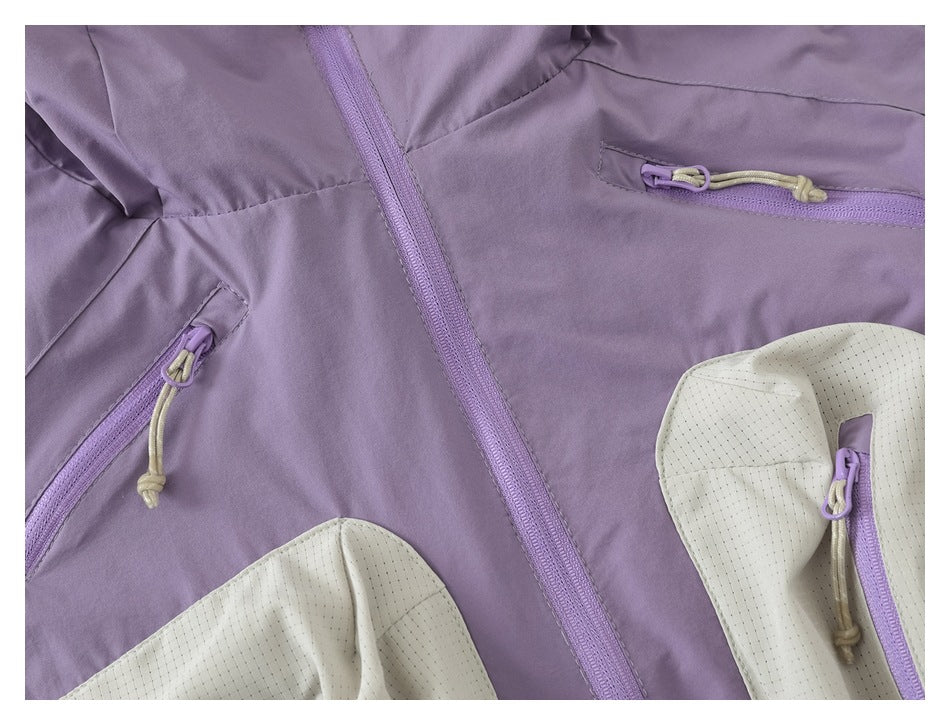 Close-up of a lavender jacket front with a central zipper, zip pockets, and cream perforated panels.