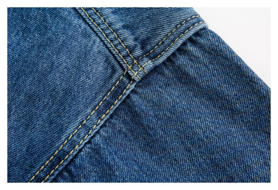 Close-up of blue denim with intersecting seams and contrasting tan topstitching.