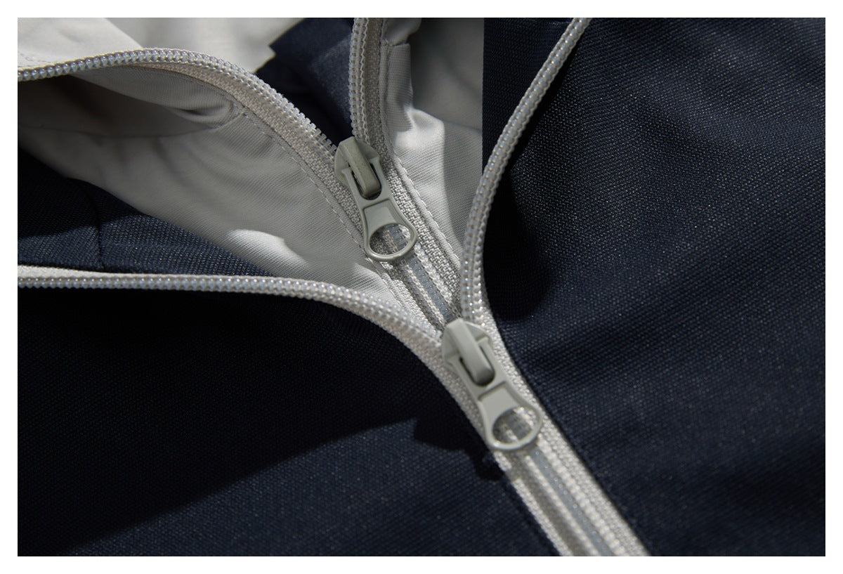 Close-up of two light gray zipper pulls and zipper tracks on a dark navy garment with pale lining.