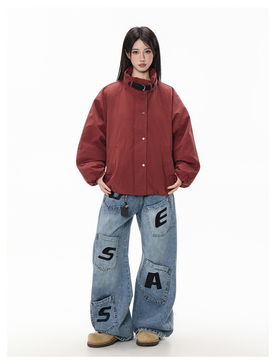 Front view of a model wearing the rust-red jacket with high collar, snap placket, roomy sleeves and pockets.