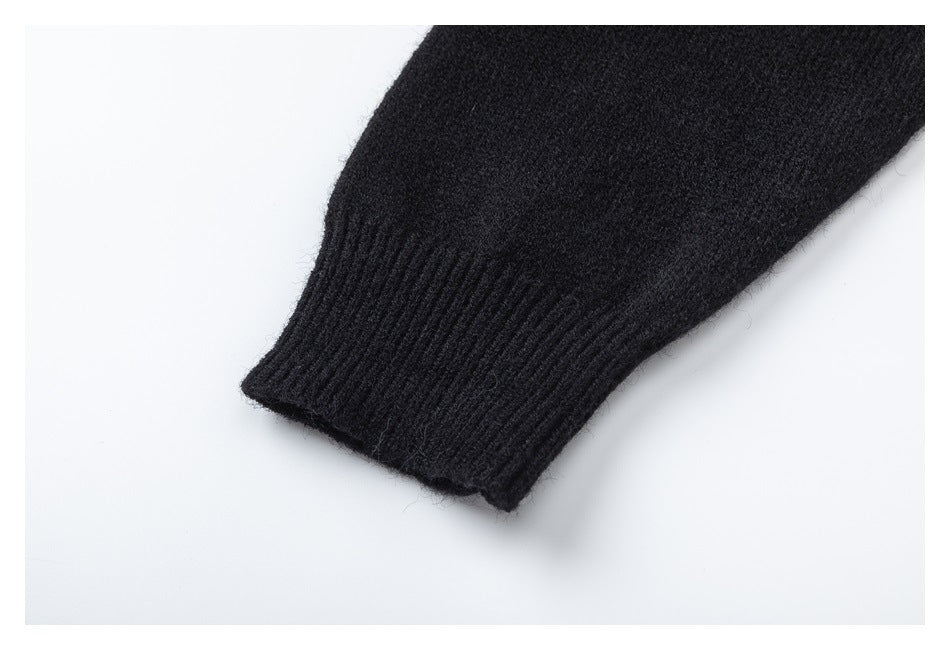 Close-up of a black knit sleeve ending in a ribbed cuff against a white background.