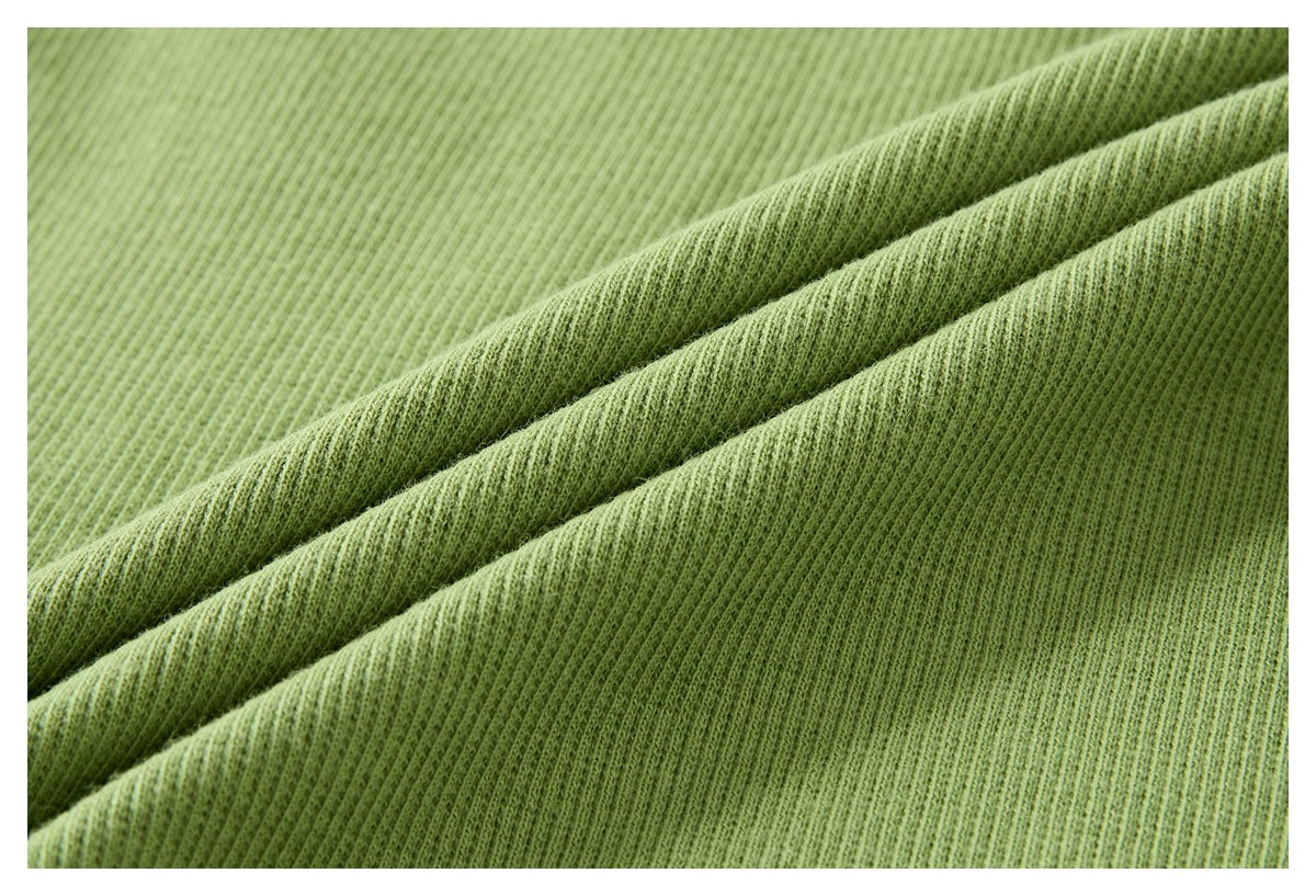 Close-up of light green ribbed fabric arranged in soft folds, showing its fine texture.