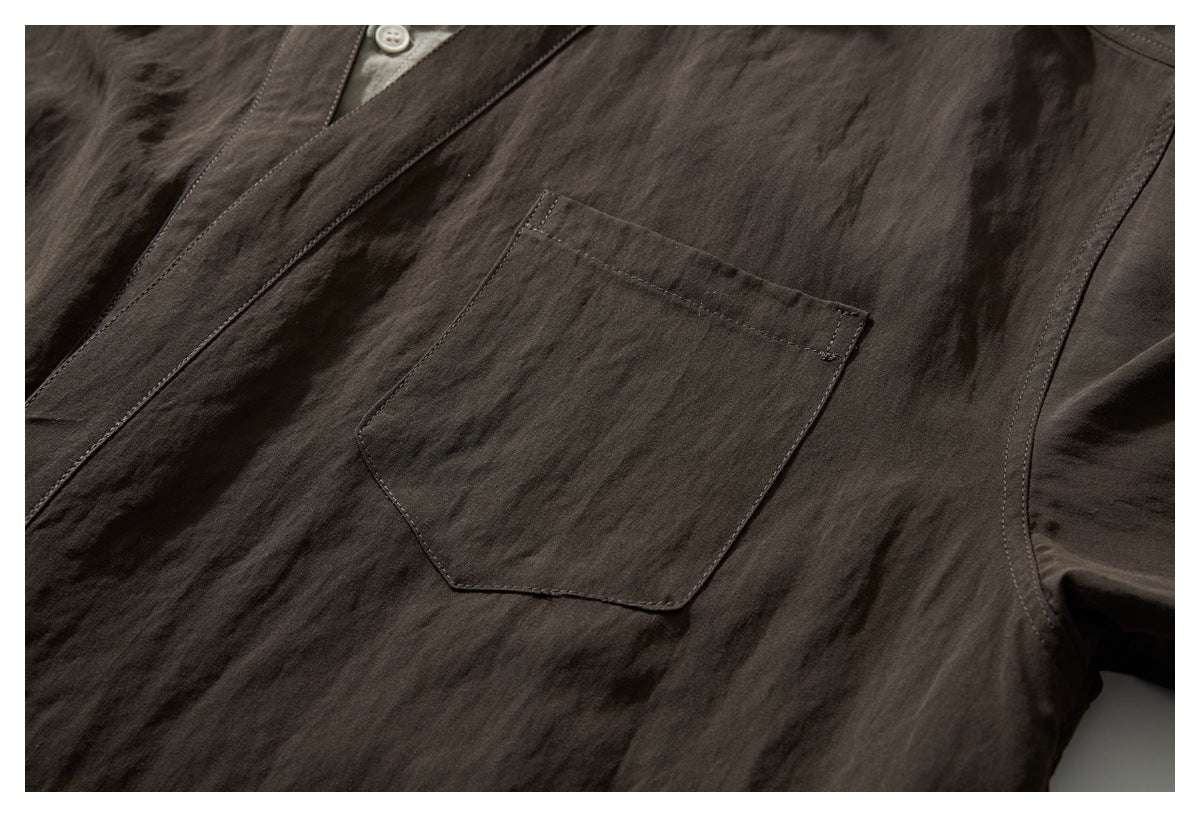 Close-up of a dark brown shirt’s stitched chest pocket and front placket.