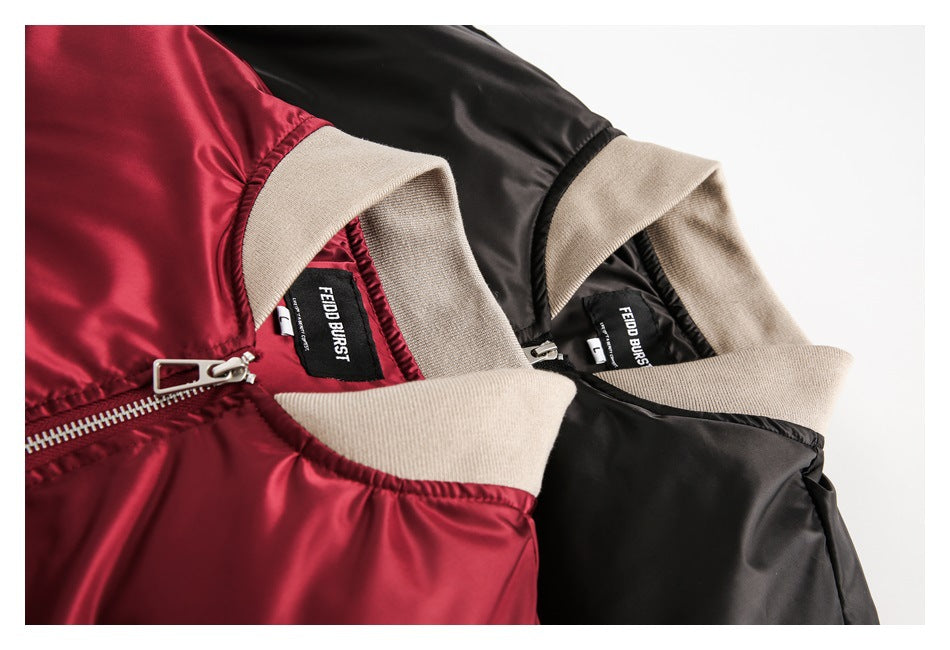 Close-up of burgundy and black bomber jackets showing beige ribbed collars, zippers, and sewn-in neck labels.