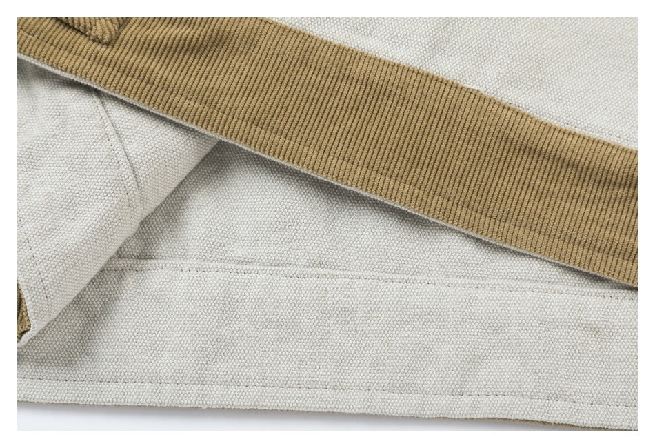 Close-up of a tan ribbed band and stitched hem on light gray fabric.