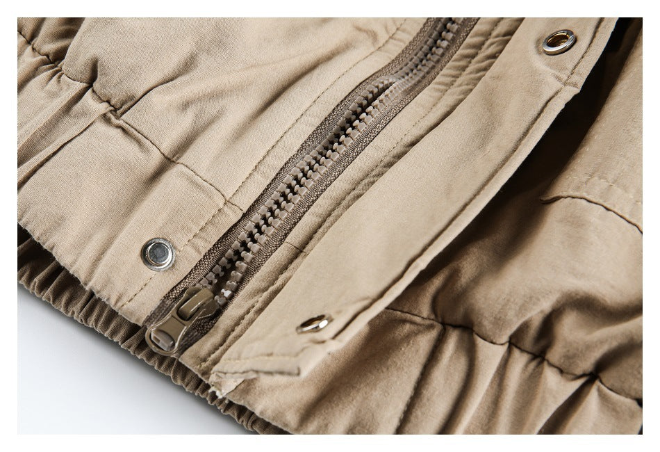 Close-up of a beige garment's zipper, snap-fastened storm flap, and gathered edge.