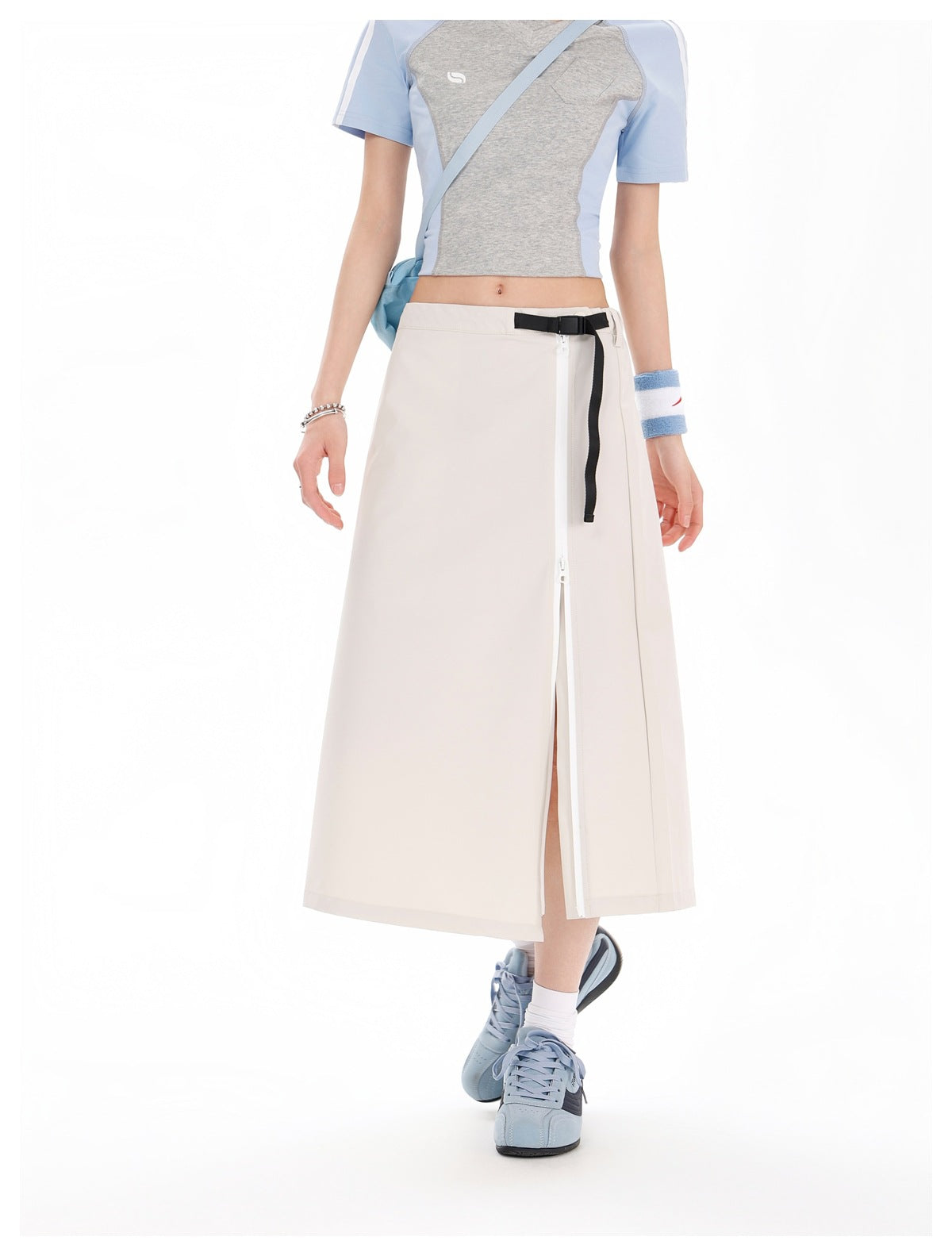 Model wearing an ivory midi skirt with a long white side zipper and black belt detail, paired with a gray and blue cropped