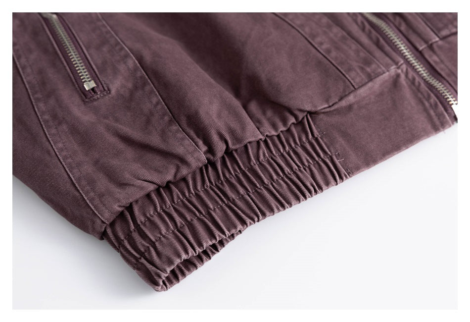 Close-up of a gathered elastic waistband and zip pockets on muted plum pants.