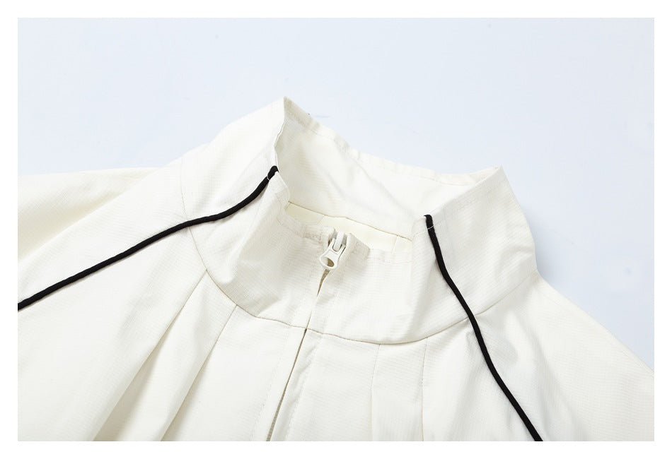 Close-up of the ivory jacket's stand collar, front zipper, and black piping.