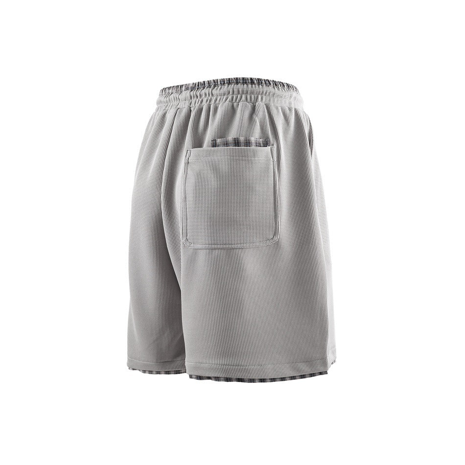 Back view of light gray waffle-textured shorts with a large patch pocket and plaid inner layer at waistband and hem