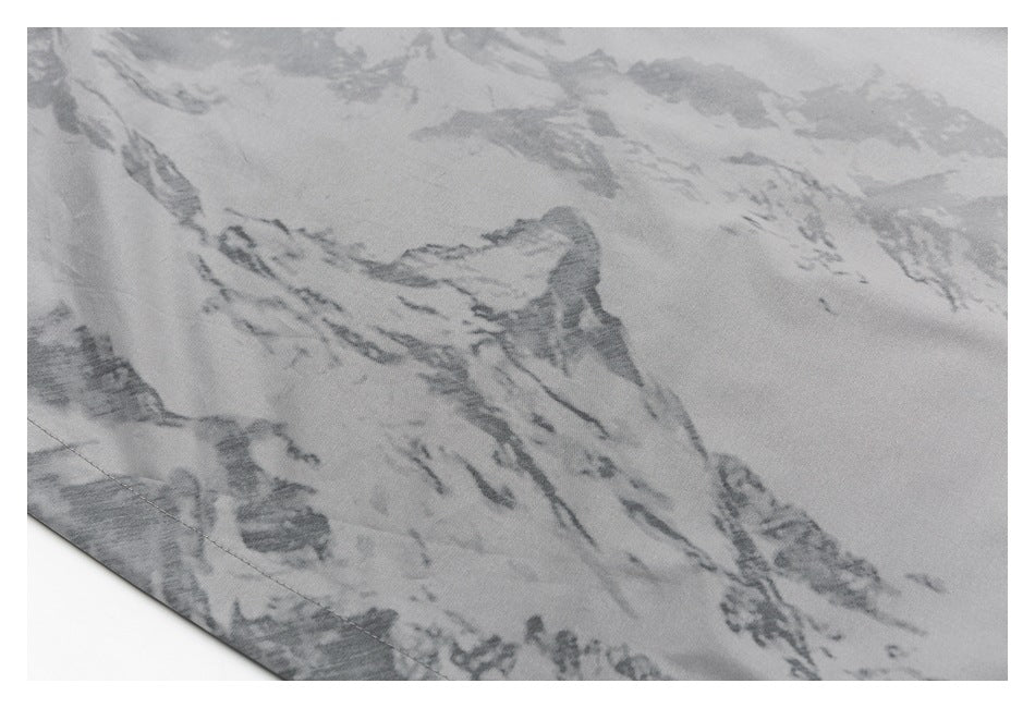 Close-up of gray fabric with a darker, marbled mountain-like print and a stitched edge.