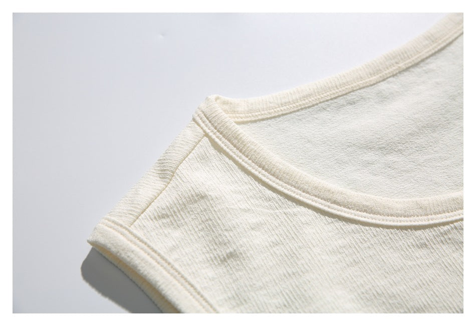 Close-up of the ivory top's scoop neckline, shoulder seam, and bound armhole.