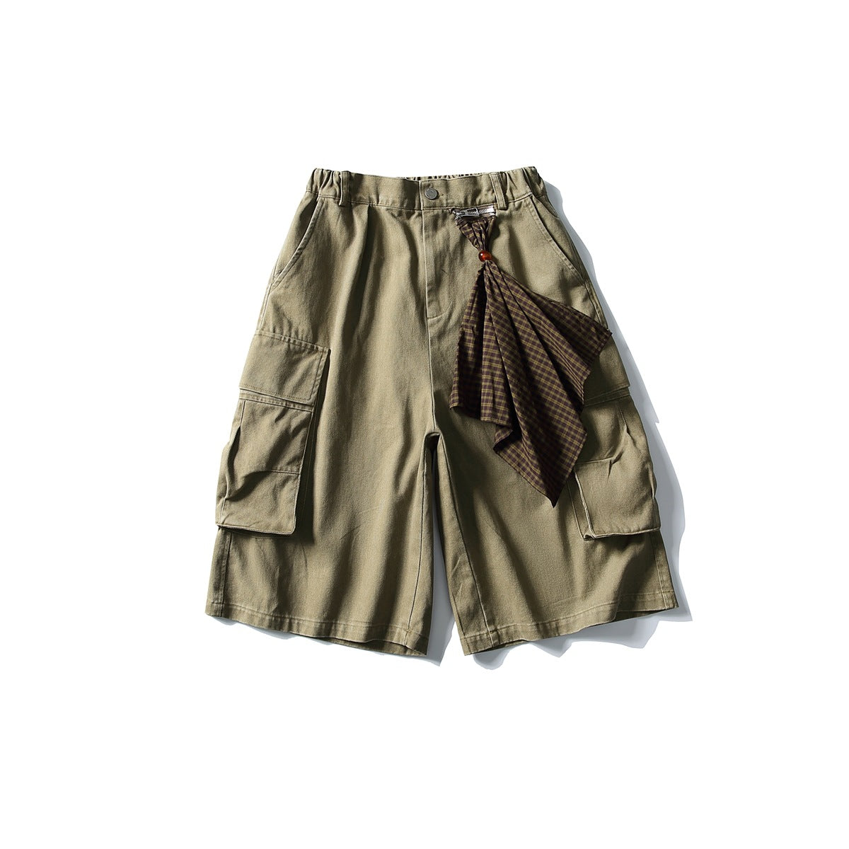 Khaki-olive cargo shorts with large side flap pockets and a brown plaid scarf attached at the front zipper