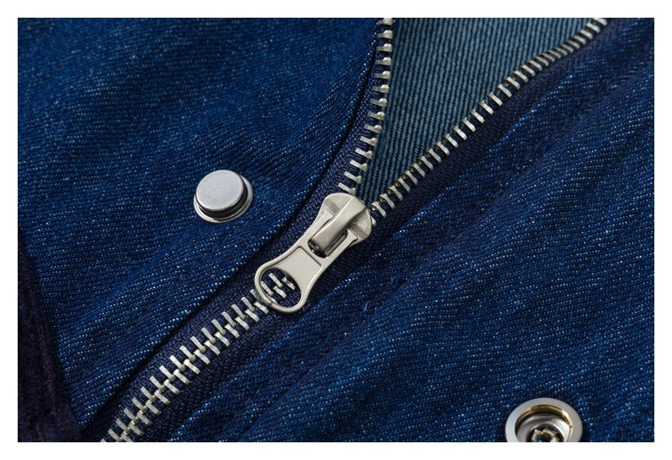Close-up of a silver zipper and snap fastener on dark indigo denim.