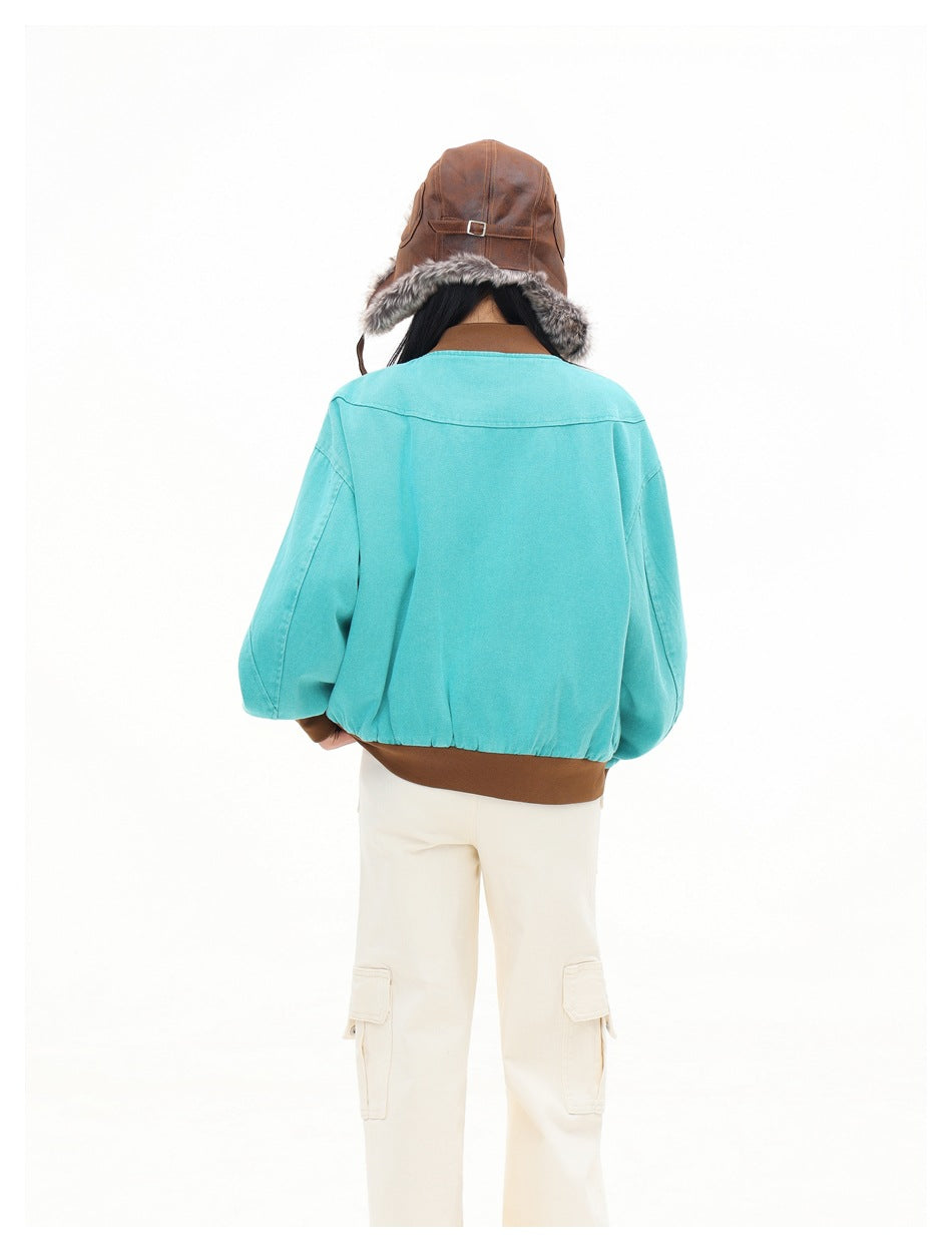 Back view of a model wearing a turquoise jacket with brown ribbed hem and a brown fur-lined hat.