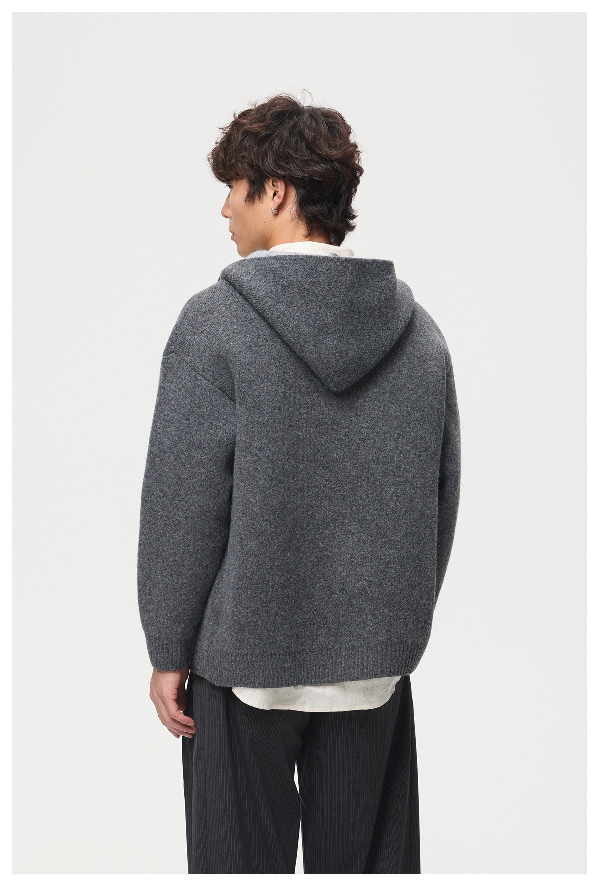 Rear view of a model wearing a charcoal gray hooded jacket with ribbed cuffs and hem.