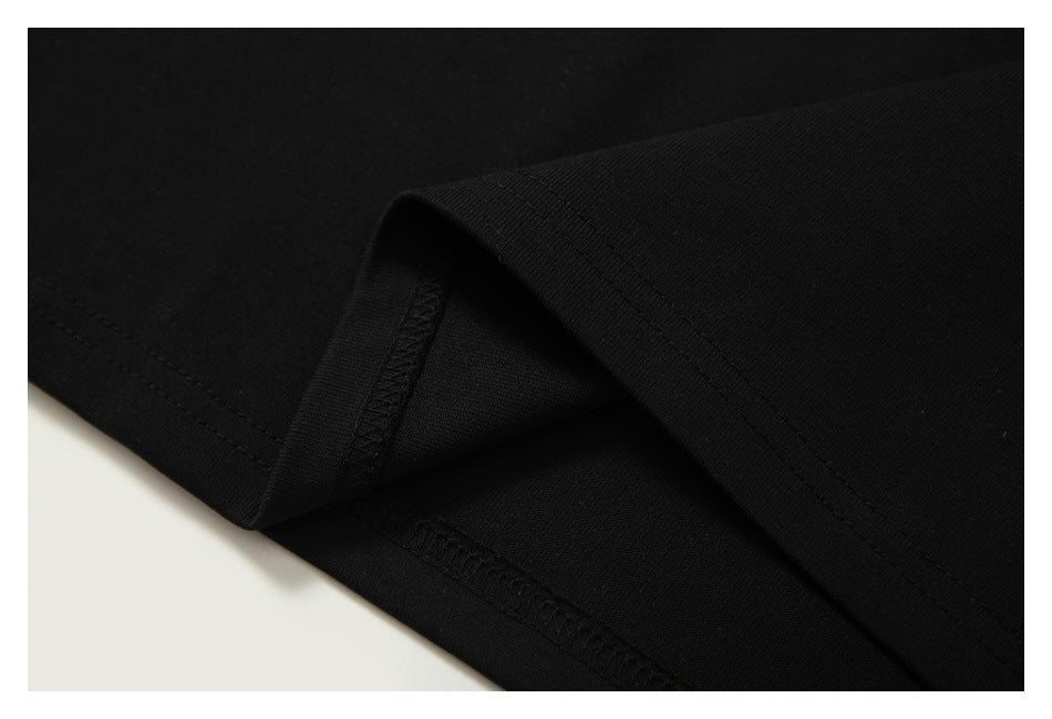 Close-up of a folded black garment hem showing the outer stitching and interior overlocked seam.