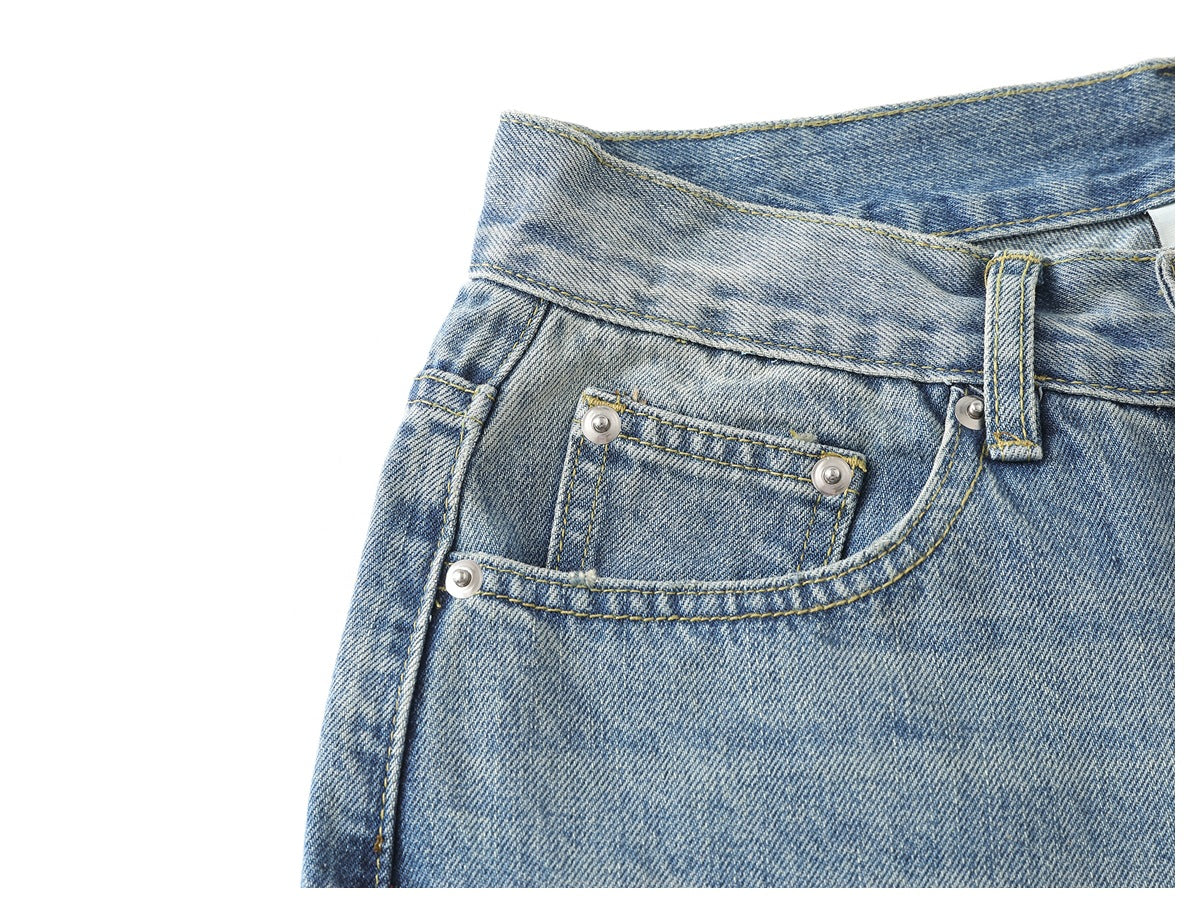 Close-up of light blue faded jeans showing the front pocket, coin pocket, belt loop and contrast stitching.