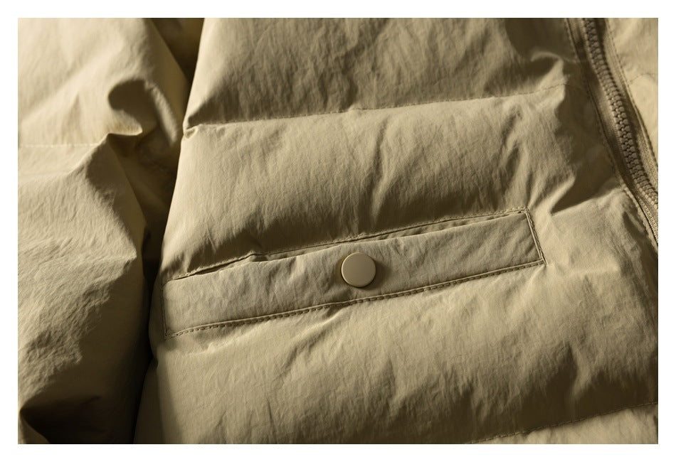 Close-up of a khaki jacket pocket with a snap-button tab and stitched seams.