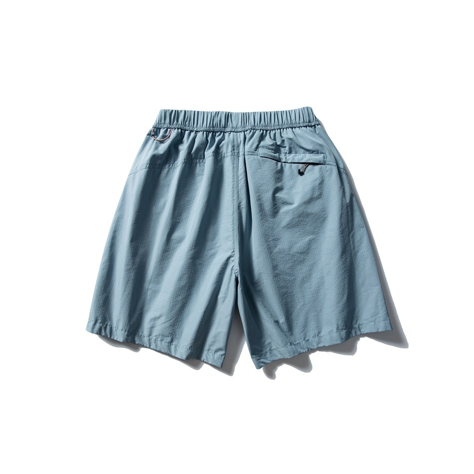 Back view of muted blue shorts with an elastic waistband and a zip pocket.