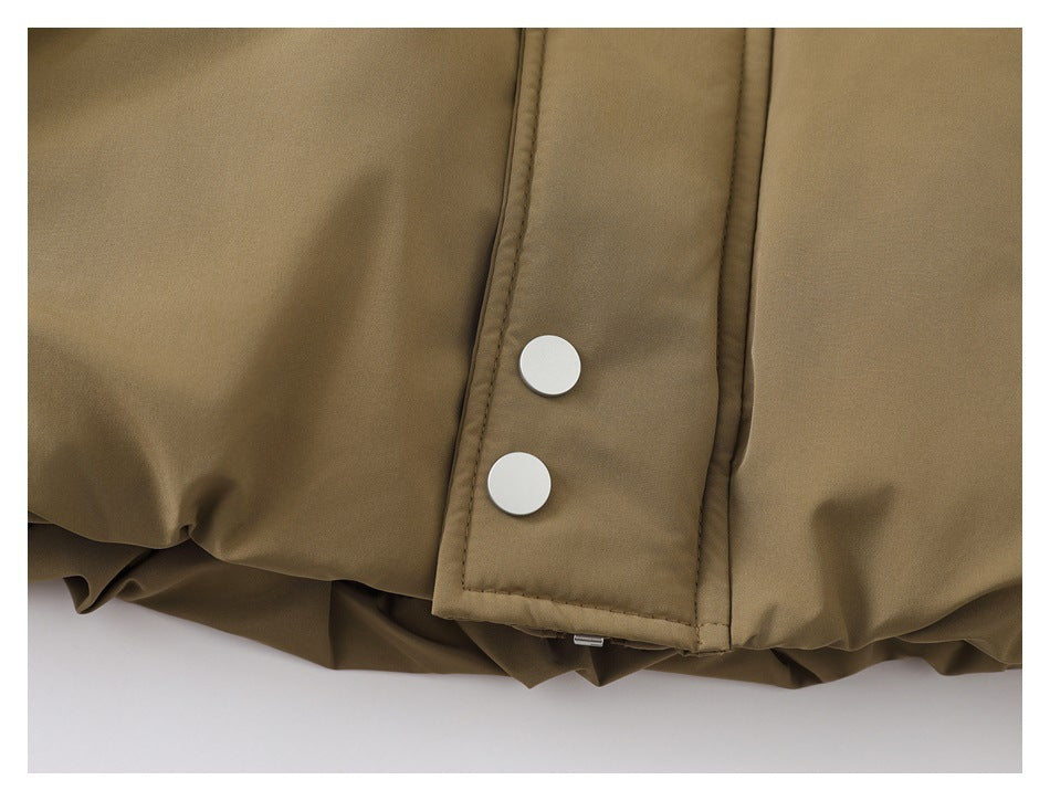 Close-up of a khaki jacket hem and snap-button placket with two white snaps.
