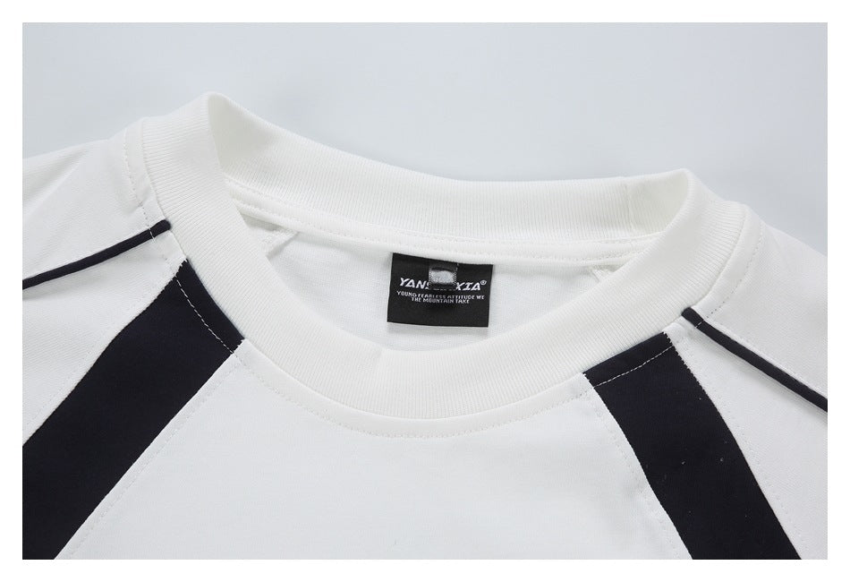 Close-up of a white crew neckline with black raglan panels and a sewn black neck label.