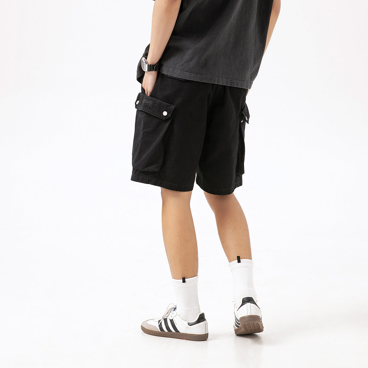 Close rear view of black cargo shorts with large flap pockets and snap closures.