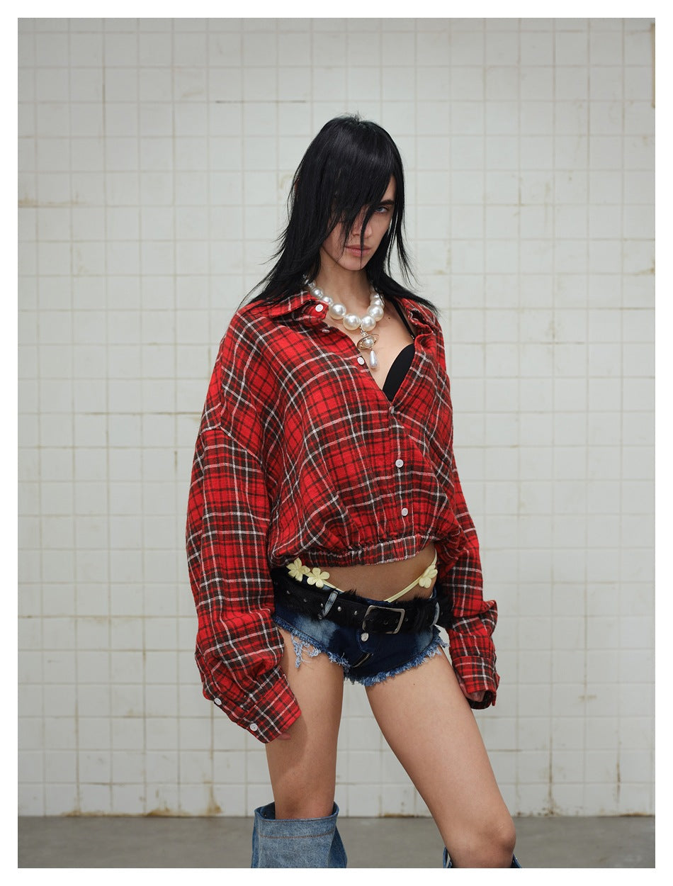 Model wearing a red plaid button-up shirt with a gathered hem and dark frayed denim shorts.