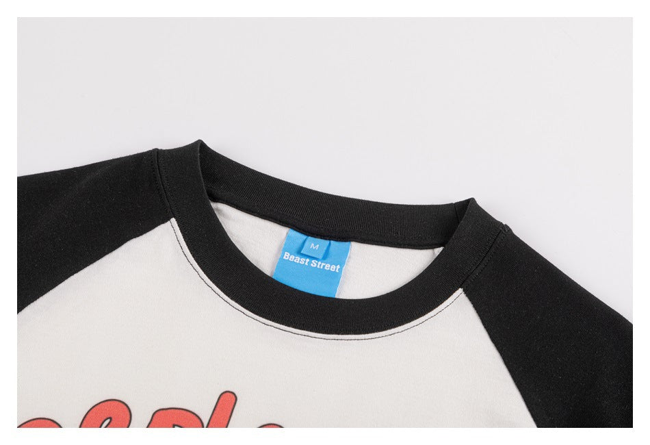 Close view of the black ribbed neckline and blue M-size brand label on an off-white raglan T-shirt.