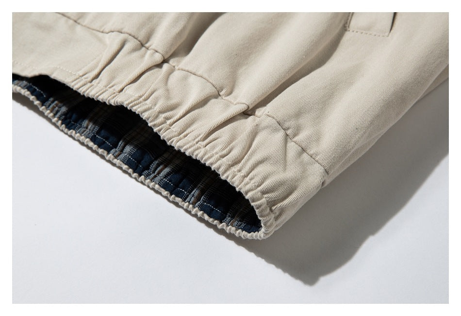 Close-up of an elasticated beige jacket hem revealing dark plaid lining.