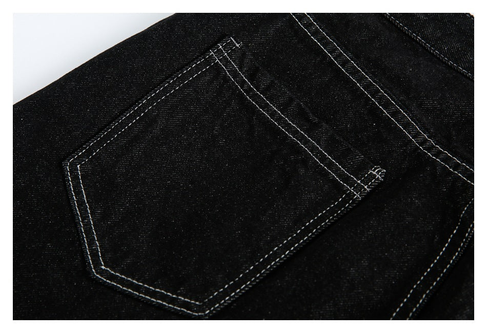 Close-up of a black denim back pocket with prominent white double stitching.